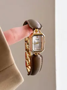 Close-up detail of a vintage gold rectangular watch featuring a brown leather strap