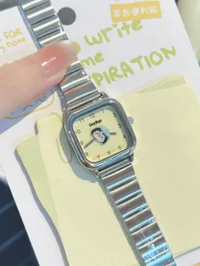 Primer plano de reloj cuadrado de acero plateado con linda esfera de dibujos de pingüino
