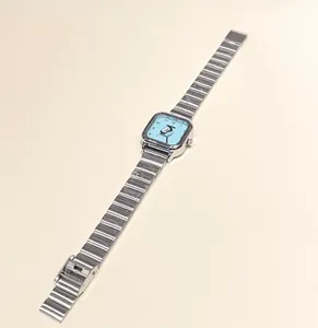 Vista detallada de un reloj cuadrado de acero plateado con una esfera de pingüino mono