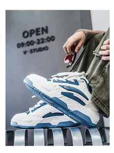 Detailopname van witte en blauwe chunky sneakers bij een model dat buiten zit
