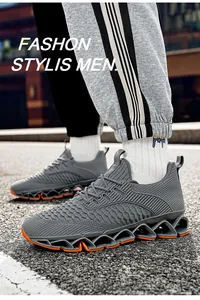 Detail van grijze ademende flyknit hardloopschoenen voor heren met oranje blad-vormige zolen.