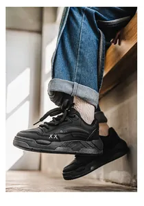 Detailopname van zwarte chunky sneakers met XX-stiksels en Ogiy-logo aan de zijkant