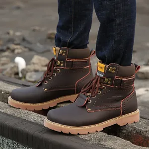 Detailed side view of men's brown leather vintage work boots on a rough outdoor surface