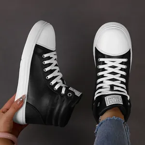 Close-up detail of black and white high-top leather casual boots with stylish tongue label.