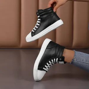 Detailed view of black and white high-top leather sneakers worn and held.