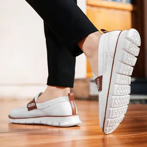 Primer plano de mocasines de malla blanca con detalles en cuero marrón sobre suelo de madera