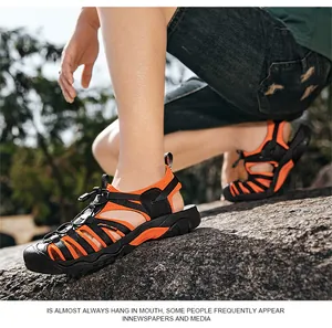 Macro view of orange and black breathable outdoor hiking sandals for men on rocks