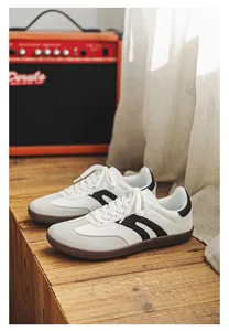 Retro minimalist wide-toe sneakers in white and grey suede on rustic wood surface