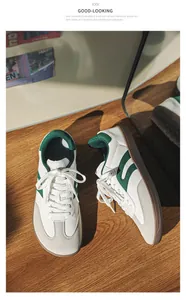 Close-up of white and green wide-toe barefoot sneakers on a natural wooden surface.