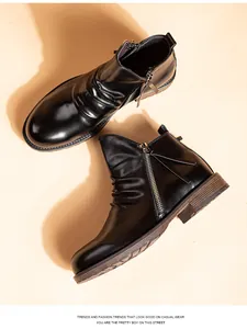 Vista detallada de botines Chelsea de cuero negro con cremallera y pliegues