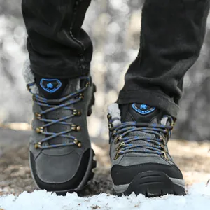 Detailed view of professional grey waterproof high-top winter hiking boots standing on snow