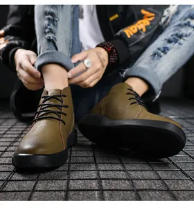 Detailed close-up of men's olive green high-top leather boots on a metal grid floor
