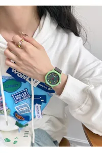 Detail of a green octagonal quartz watch on wrist with a white hoodie