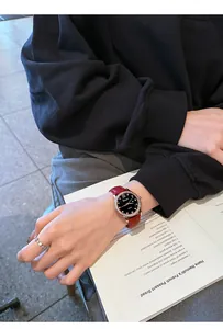 Elegante reloj Dimini con correa de cuero roja y esfera estrellada usado en la muñeca