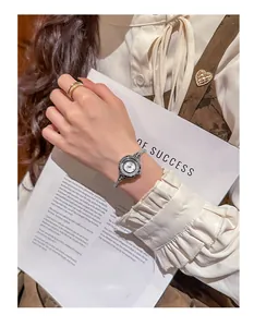 Detailed close-up view of elegant silver watch with rhinestone bezel on a woman's wrist.