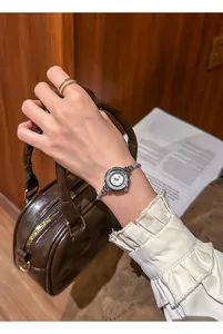 Detailed view of silver ladies' rhinestone fashion watch on wrist with brown handbag