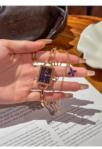 Detailed view of fashionable rose gold alloy watch and blue flower charm bracelet.