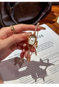 Detail of rose gold fashion watch with rhinestone accents and adjustable drawstring strap.