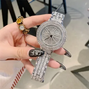 Luxury iced out turntable watch for women with sparkling crystal wheel dial and steel band.
