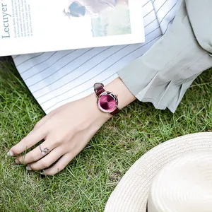 Close-up of a stylish women's quartz watch with a wine red dial on a leather strap
