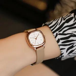 Close-up of elegant small square watch with rose gold case and beige leather strap