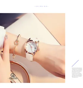 Close-up of GUOU women's watch with white leather strap and rhinestone markers on the dial