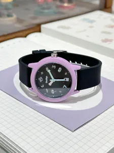 Detalle de un reloj de cuarzo púrpura con correa de silicona negra sobre un cuaderno