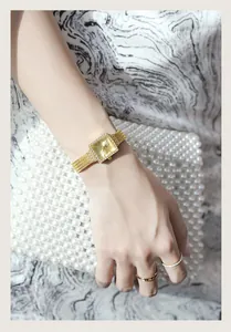 Elegant gold square quartz watch with rhinestone bezel and mesh band on model's wrist