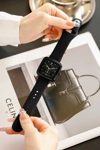 Close-up of black silicone TICTOC watch held by hands against a magazine backdrop