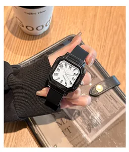 Primer plano de un reloj de cuarzo cuadrado con correa de silicona negra en la mano.