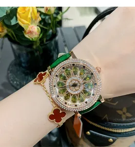 Détail d'une montre de luxe pour femme avec pierres vertes, lunette diamant et bracelet cuir.
