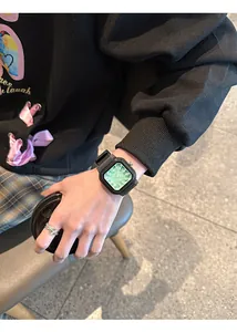 Primer plano de un moderno reloj de cuarzo cuadrado verde con correa de silicona negra