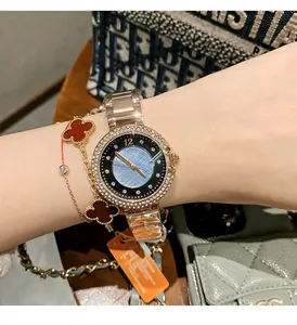 Nahaufnahme einer goldenen Dinimi Armbanduhr mit Strass und Kleeblatt-Armbändern