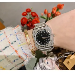 Elegant silver octagonal quartz watch on a wrist with a gold bangle and ivory fuzzy sweater.