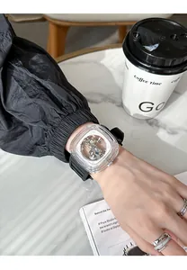 Close-up of a GUOU square mechanical watch with a transparent case and black silicone strap.