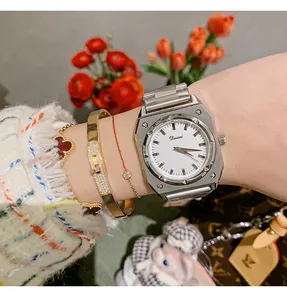 Detailed shot of Dinimi silver octagonal quartz watch styled with gold bracelets