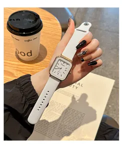 Primer plano de un elegante reloj de cuarzo cuadrado con correa de silicona blanca y fecha