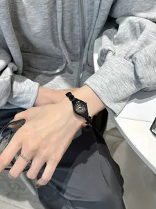 Detail shot of a minimalist GEDI black alloy bracelet watch worn on a wrist with a silver ring