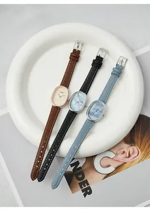 Detalle de relojes ovales con esfera de nácar y correa de cuero en un plato blanco