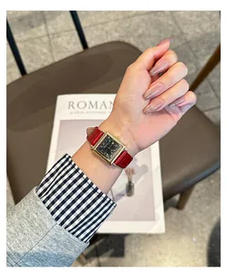 Detail of a vintage-style GUOU square watch with a red leather strap on a wrist.