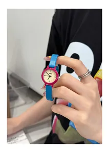 Close-up detail of a colorful small round quartz watch with pink case and blue leather strap