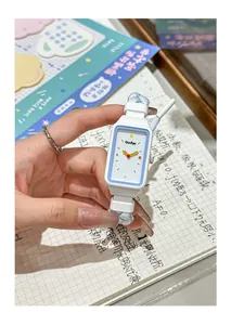Detalle de un lindo reloj rectangular blanco con correa de cuerda trenzada azul.