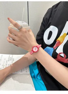 Detailed close-up of a stylish pink round watch worn on a wrist in a lifestyle setting