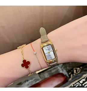 Detailed shot of an elegant gold rectangular watch paired with stylish gold bracelets