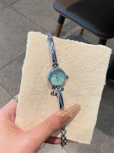 Detailed view of GEDI silver bangle watch with mint green dial on textured paper