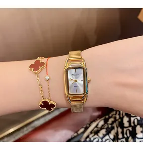 Detail of Dimini vintage gold square watch styled with clover bracelet on wrist