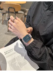 Vista detallada de un elegante reloj de cuarzo cuadrado con correa de silicona gris en la muñeca.