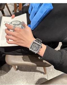 Primer plano de un reloj de cuarzo cuadrado con correa de silicona negra en una muñeca