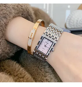 Detail van Dinimi rechthoekig horloge met roze wijzerplaat en gouden Kelly-armband