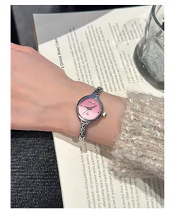 Dettaglio dell'orologio al quarzo GUOU con quadrante rosa e cinturino a catena argento sul polso.